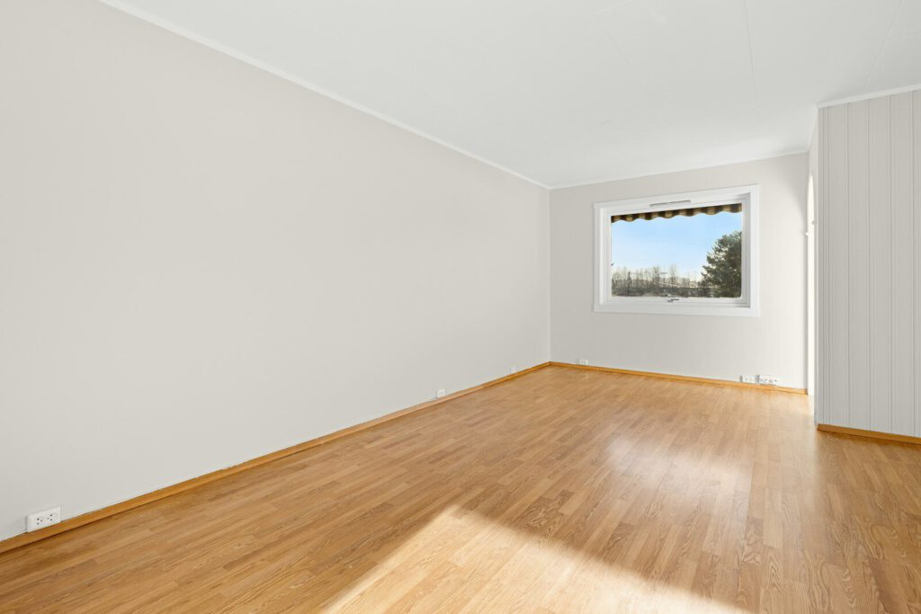 An empty room with hard wood floors and a window